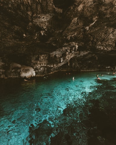 人们在有洞穴的水体上游泳的照片